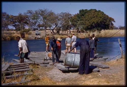 Manuel and John Namabue loading barrels on the pont (ferry) at Bagani