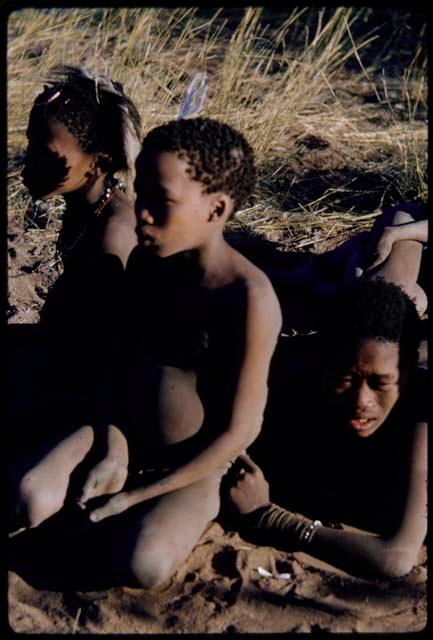 Children, Groups, play: /Gunda (husband of N!ai) lying down, with Tsamgao (son of ≠Toma) and an unidentified boy sitting next to him