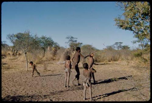 Children, Toys: Boys playing with a djani (helicopter toy), with a little boy wearing dance rattles in the distance