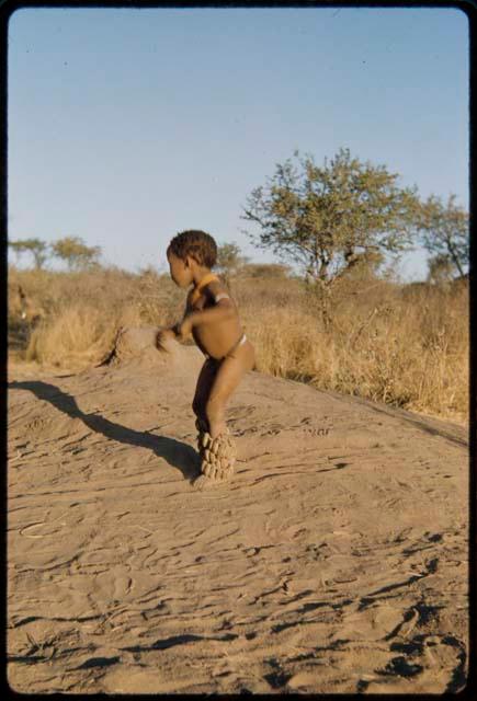 Children, Dancing: Little boy dancing on a termite mound with his dance rattles