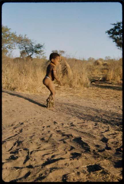 Children, Dancing: Little boy dancing on a termite mound with his dance rattles