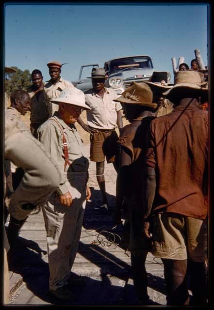 Men standing with Laurence Marshall at the pont (ferry) at Bagani, with an expedition truck in the background