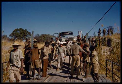 Men standing with Laurence Marshall at the pont (ferry) at Bagani, with an expedition truck in the background