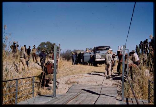 Men standing near an expedition truck boarding the pont (ferry) at Bagani