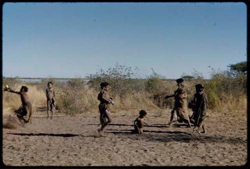 Children, Groups, play: Girls playing Tamah n!o’an (the ball game) in a dance circle area, with a pan filled with water in the distance