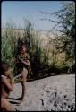 Children, Socialization--hunting, carrying: Two boys standing next to the Gautscha waterhole, with the pan in the background