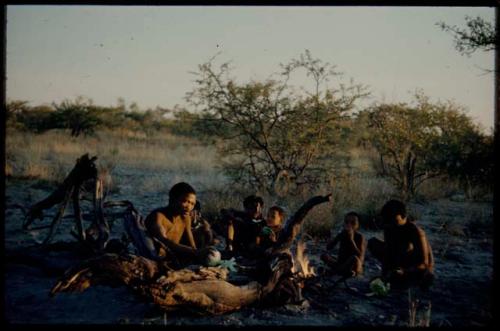 Fire, Evening: ≠Toma and "Gao Medicine" sitting by a fire with other people, eating melons