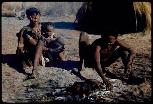 Food, Cooking: Dam and his wife, ≠Gisa, sitting and cooking veldkos in their fire