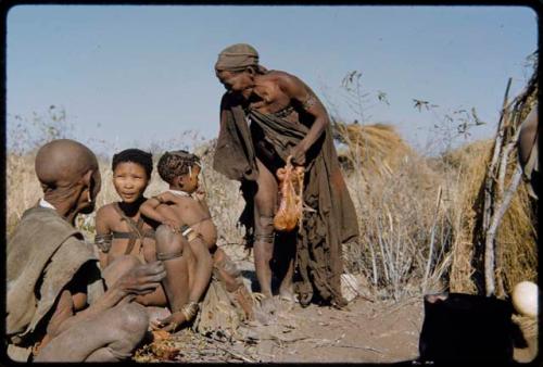 Food, Cooking: Woman holding animal entrails about to sit down with /Naoka ("/Qui Hunter's" wife) and her mother "Old /Gasa"