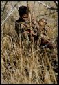 Food Gathering, Children: Bau of Band 10 digging in the grass, with her child tied to her back