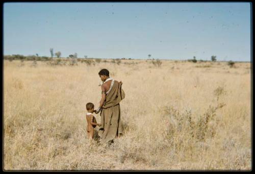 Food Gathering, Children: Woman gathering tsi, handing something to a child, view from behind