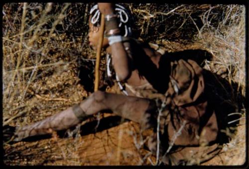 Food Gathering, General: Woman sitting and reaching into a hole she has dug