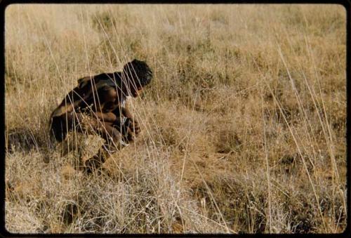 Food Gathering, Men:  /Qui (husband of Khuan//a) crouching in the grass