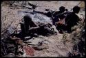 Food Gathering, Tsi: Women lying by the ashes of a fire, with a pile of tsi on the ground near them