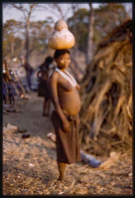 Woman carrying gourd of water on her head (out of focus)