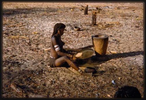 Woman sorting grain, seated profile