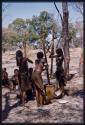 Three girls pounding millet, seen from behind