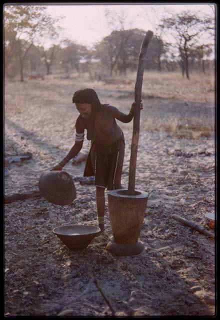 Woman standing with mortar and meal in a basket