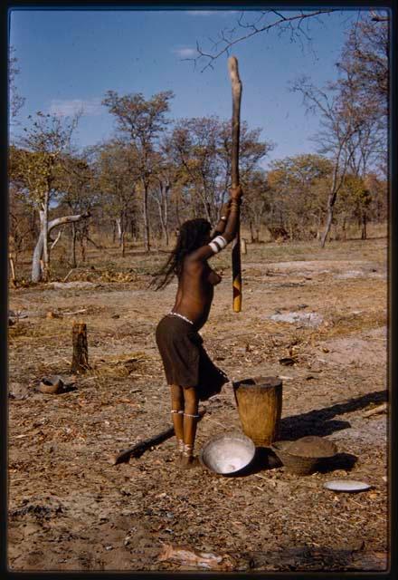 Woman pounding millet, profile