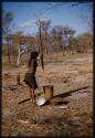 Woman pounding millet, profile