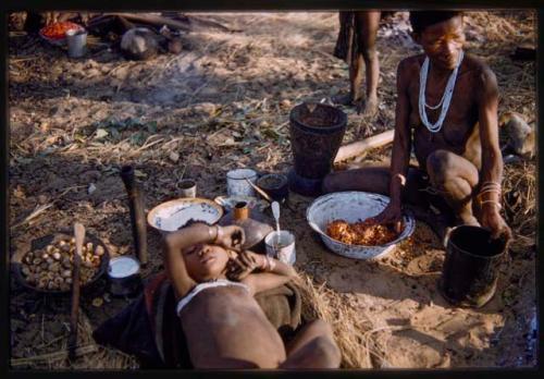 Mushulay dividing meal, with a boy lying in front of him