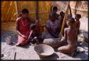 Group of women and children pounding meal in log