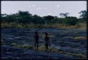 Two boys walking along the edge of the pan, seen from behind