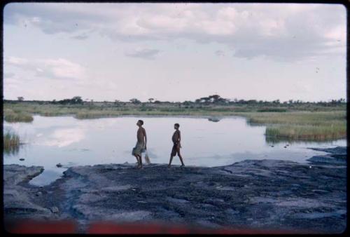 Two boys walking along the edge of the pan, profile