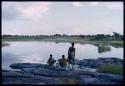 Three boys at the edge of the water, seen from behind