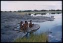 Three boys sitting at the edge of the water