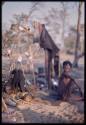 Woman sitting by skerm with tin cans hanging on it