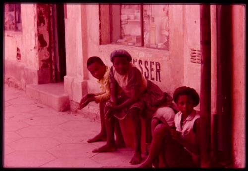 Three young people sitting in front of a store