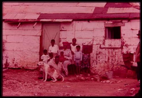 Philip Hameva and Olga (his wife) with their children and dog in front of their house, distant view