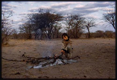 Deborah Marshall squatting near campfire