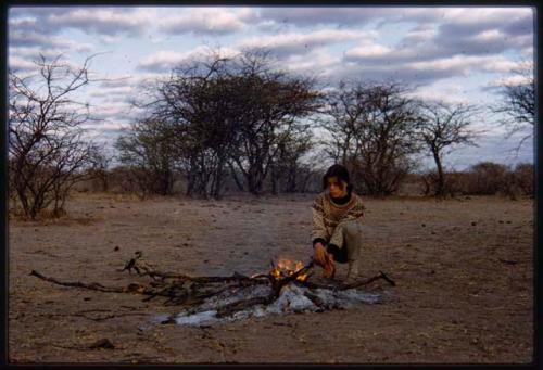 Deborah Marshall squatting near campfire