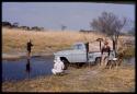 Chevrolet truck crossing at ford, with three men watching it