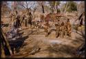 Children standing around meat hung on a trellis