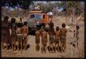 Children standing in a line facing the expedition Dodge, seen from behind