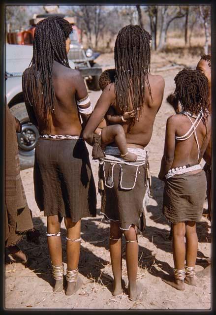 Women and children standing in a line, seen from behind