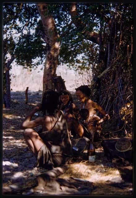 Women and children sitting under trees