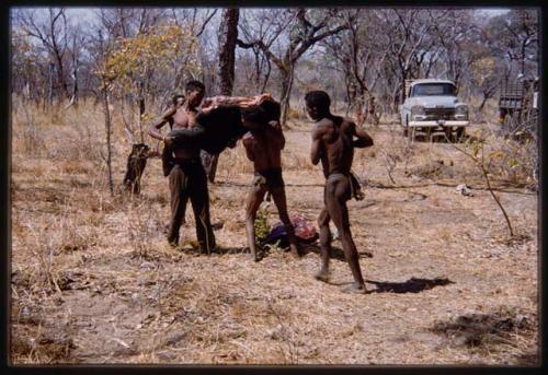 Two men carrying buffalo meat, other people in the background