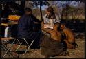 Nicholas England writing in a notebook, sitting with Kernel Ledimo, Hu/Na, and Kumsa