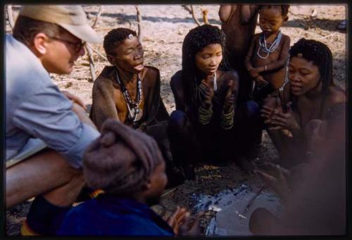 Group of women clapping; Nicholas England and Kernel Ledimo sitting with them