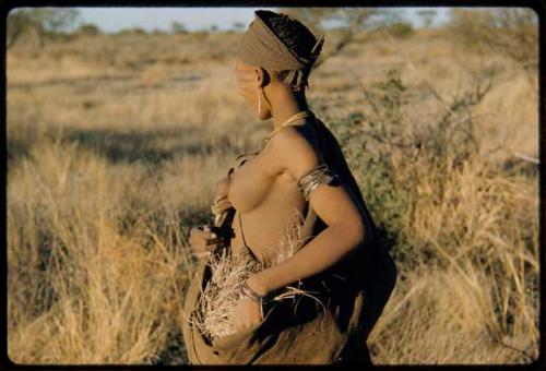 Grass: Woman standing, carrying a kaross full of grass used for bedding, close-up