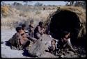 Groups: People sitting in front of Gau's skerm, including "/Qui Hunter" cooking (inside the skerm), "Old Gau" squatting by the entrance, //Khuga (wife of !Naishi), /Naoka, "Old /Gasa" with shaved head, /Qui (son of Gau and Khuan//a), and Be (Gau's first wife)