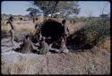 Groups: People sitting in front of Gau's skerm, including two boys standing, /Naoka, "Old /Gasa" with shaved head and Be (Gau's first wife)