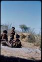 Groups: //Kushay sitting, resting her legs on a stamping bowl, with "Little ≠Gao" standing and N!ai sitting next to her