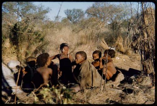 Groups: Group of /Ti!kay's family members sitting, including Bau (/Ti!kay's daughter, center), children, /Naoka and /Goishay's sister (the mother of /Ti!kay's wives)