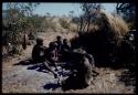 Groups, Men: Men sitting in front of a skerm, including !Naishi of Band 5 wearing a hat, "Old Demi" of Band 6 (left) and "/Gao Music" pounding something with a metal tool on a stone