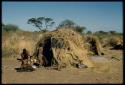 Groups, Extended Family: "Old ≠Toma" sitting with other people in front of Gau's skerm, with a kudu head on the ground next to the skerm